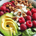 Raspberry-Spinach Salad with Avocado and Walnuts: A Fresh Twist on a Classic Dish 4 Close-up of a raspberry-spinach salad with creamy avocado slices, crunchy walnuts, feta cheese, and fresh raspberries in a white bowl.